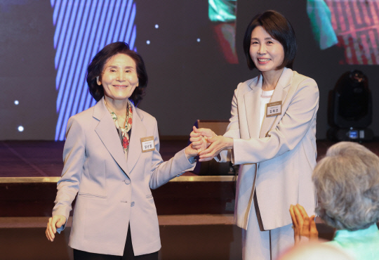 국민의힘 김문수 대선 후보의 부인 설난영 씨와 더불어민주당 이재명 대선 후보의 부인 김혜경 씨가 12일 서울 중구 신라호텔에서 열린 중앙신도회 창립 70주년 기념식에서 손을 맞잡고 있다. 연합뉴스